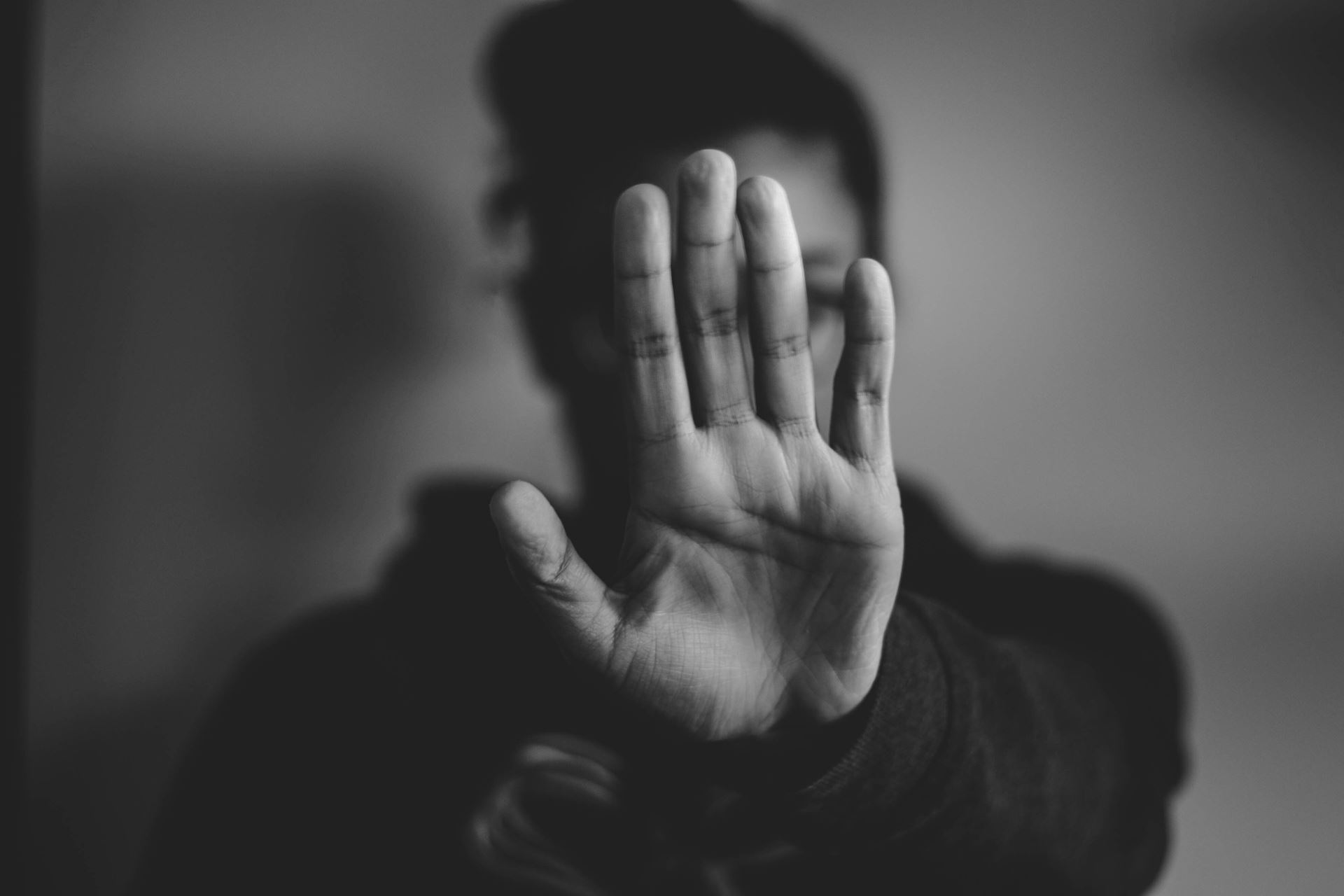 Person holding up hand in front of face